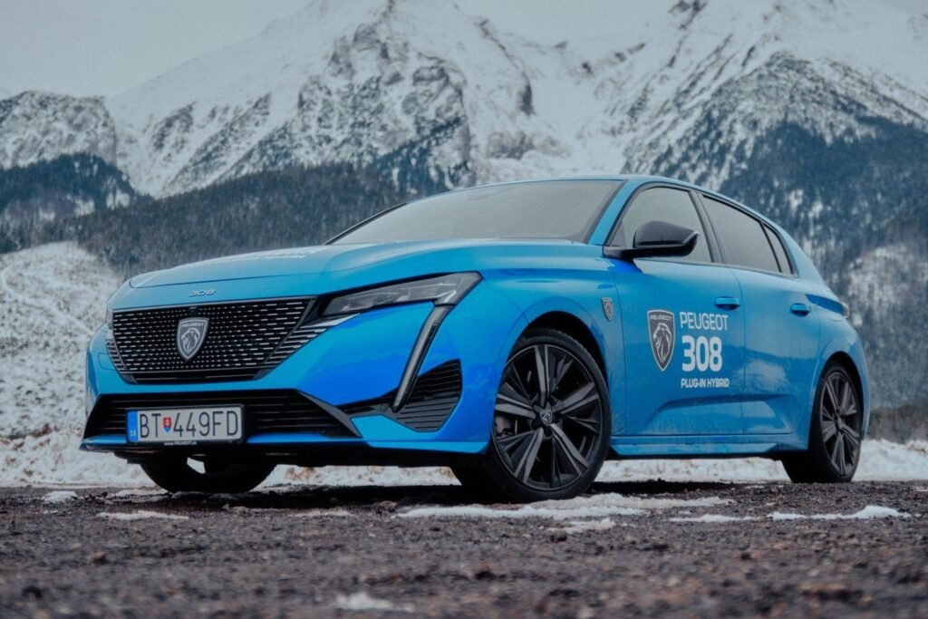 Peugeot bleue devant un massif montagneux