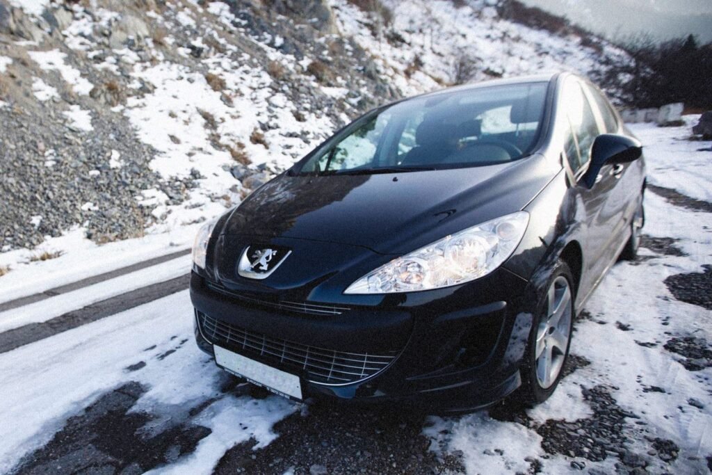 Peugeot noire, trois quarts avant sous la neige